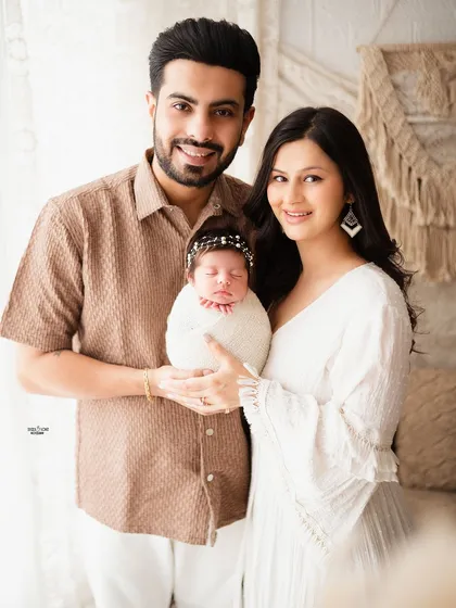 A complete family portrait with their newborn, all smiling happily for the camera.