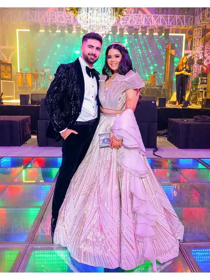 A posed portrait of the couple on a colorful, lit-up dance floor. This image showcases their glamorous reception outfits and the grand scale of their celebration.