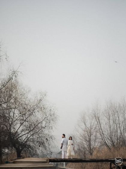 Looking up at the sky together, surrounded by the stark beauty of winter trees in Kashmir. This is a moment of shared peace and reflection, captured in a simple yet powerful pre-wedding photograph.