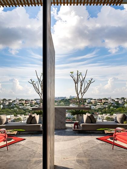 A reflected view of a rooftop terrace, showcasing the open sky, comfortable seating, and curated plants. The design creates a perfect urban vibe for relaxation and enjoying the city views.