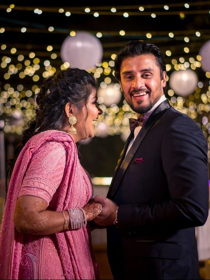 A candid shot of the couple sharing a laugh at their reception. The bokeh from the string lights creates a magical atmosphere.
