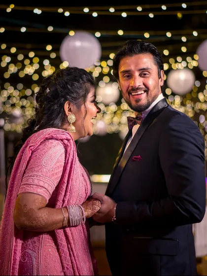 A candid shot of the couple sharing a laugh at their reception. The bokeh from the string lights creates a magical atmosphere.
