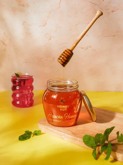 A vibrant and refreshing setup for this honey product. The combination of yellow and pink backgrounds with fresh mint leaves creates a summery feel.