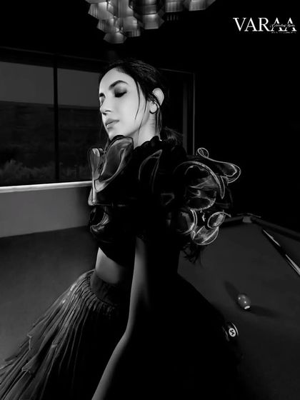 A dramatic, black-and-white shot from the Varaa Magazine editorial. The focus is on the incredible texture and structure of the ruffled top, creating a moody and artistic image that highlights the couture elements of the design.
