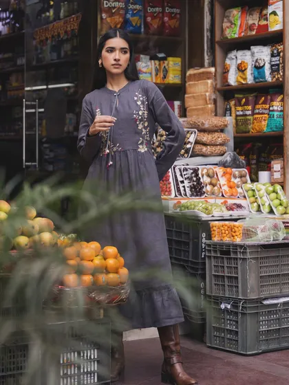 A campaign for a sustainable fashion brand, shot on location at a local market. The embroidered grey dress blends beautifully with the rustic, everyday environment.