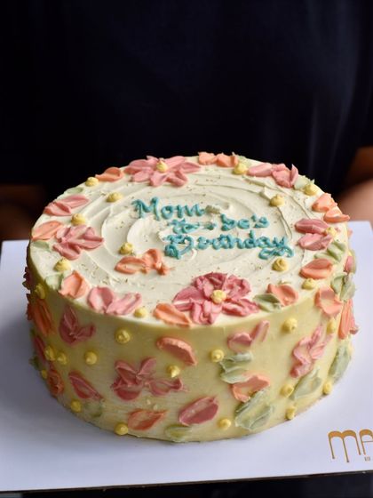 A beautiful custom cake for a mom's 90th birthday. We worked with the family to create this special design with soft, impressionistic buttercream flowers, making it a memorable part of their celebration.