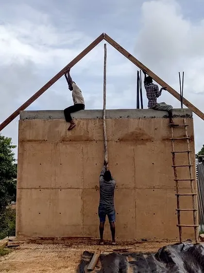 The construction of the Unnathi Farm pavilion, with my team raising the timber roof structure onto the earthen walls. This shows the hands-on nature of my design and build process.
