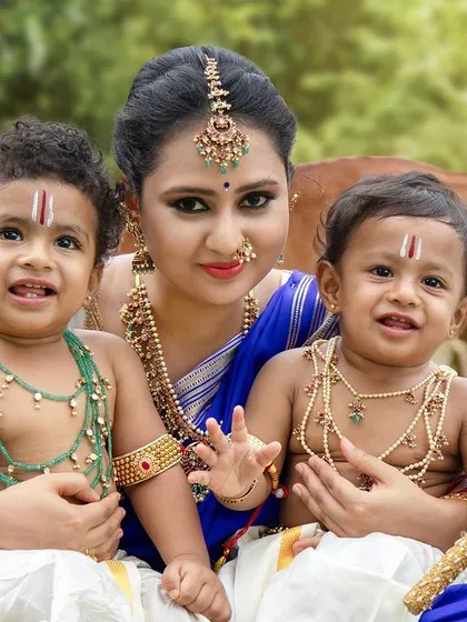 A close-up of a mother with her two adorable little Krishnas, showcasing the intricate details of their costumes and the joy on their faces.