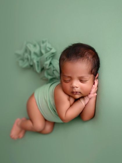 The same pose, showing the full body. This is a classic newborn pose that highlights their tiny, curled form.