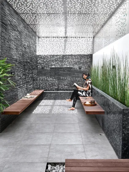 I designed this serene terrace lounge as a private retreat within a bustling city. The space features a perforated roof that creates a beautiful play of light and shadow, slate stone walls, and built-in wooden seating, embodying my love for biophilic design.