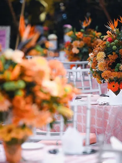 The dining tables at the garden Mehendi were adorned with lush floral centerpieces in shades of peach and orange. The soft pink linens complemented the Pantone 'Peach Fuzz' theme perfectly.