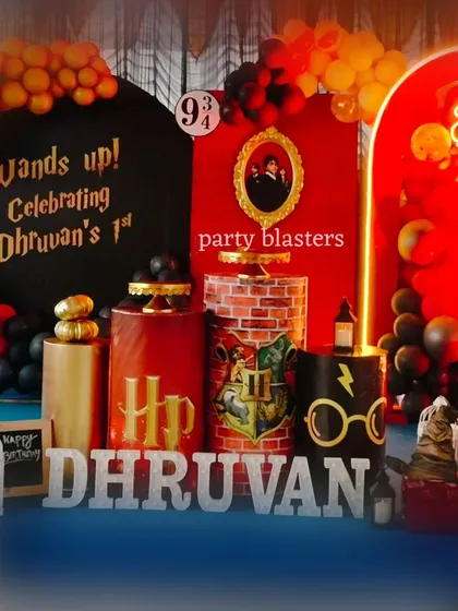 Wands up for a magical Harry Potter first birthday. This detailed setup features iconic elements like the Platform 9 3/4 sign, a Sorting Hat, themed pedestals, and a custom "Wands up!" backdrop, all in the classic Gryffindor colors.