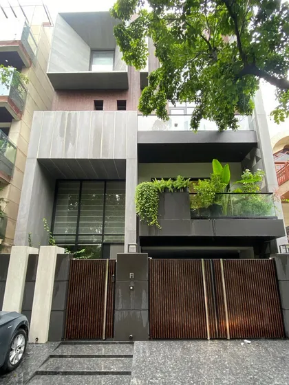 This is the final constructed home, bringing the 3D concept from image 26 to life. The interplay of volumes, the cantilevered balcony with greenery, and the wooden gate are all executed as per the detailed architectural visualization.