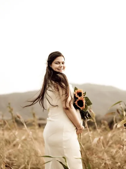The mom-to-be looks back over her shoulder with a beautiful smile, her hair catching the golden light. It's a perfect candid moment, full of warmth and joy.