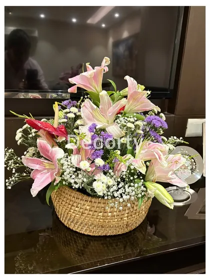 A stunning floral arrangement in a woven basket, part of the decor for a butterfly-themed celebration.