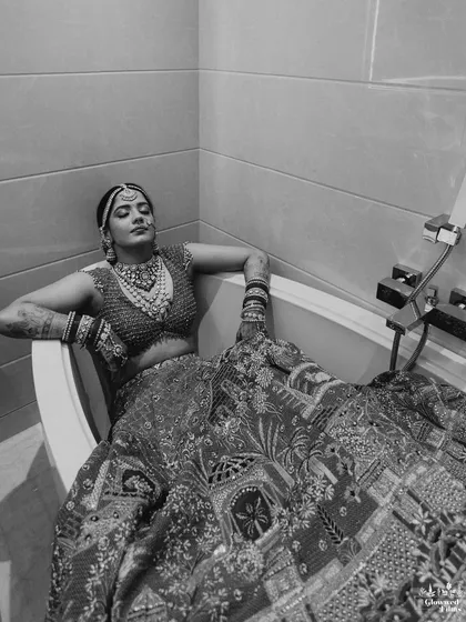A modern and edgy bridal portrait of Kriti, posing in a bathtub in her full wedding lehenga, showcasing her bold and fun personality.