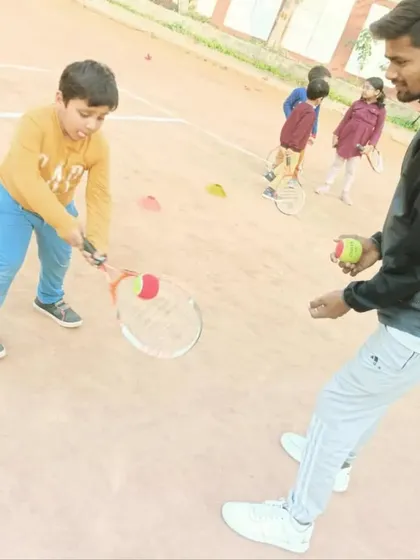 A coach provides hand-fed balls to a young student to work on his forehand technique. This focused practice helps correct small mistakes early on.