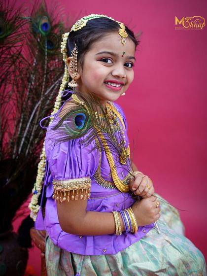 A joyful and radiant smile from the little girl in her traditional attire. The long, braided hairpiece ('jade') is a key element of this beautiful cultural look.