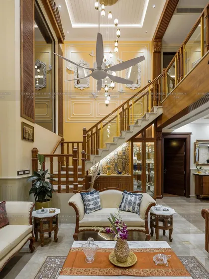 A beautiful traditional wooden staircase with Italian marble steps, leading up to a double-height window.