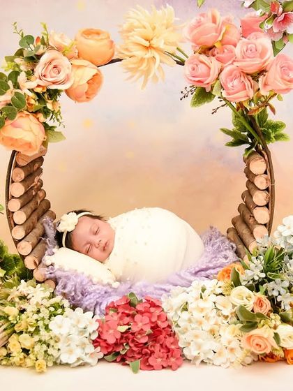 A wide shot of the rustic floral prop, showing the full arrangement of flowers and branches that create a beautiful frame around the sleeping baby.
