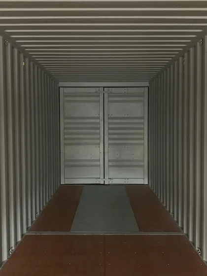Looking down the length of an empty container toward the sealed cargo doors. This vast, open space is the starting point from which we can build any floor plan you can envision.