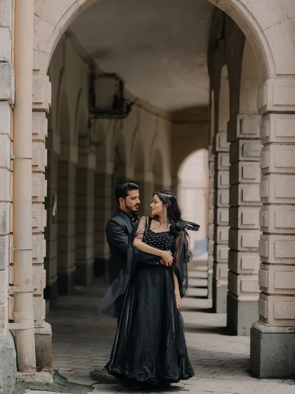 A candid moment of the couple sharing a look within an architectural corridor. The play of light and shadow adds to the romantic, story-like feel of the photograph.