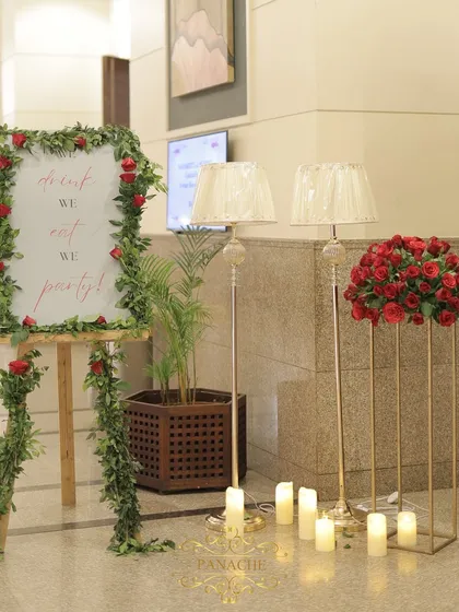 The entrance decor for the after-party, featuring the welcome sign, floor lamps, and arrangements of red roses.