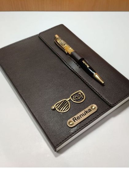 A brown personalized leather diary and pen set with a '2023' glasses charm.