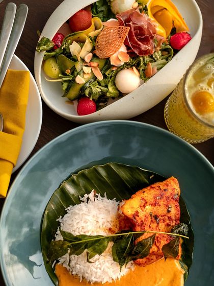 A top-down view of our diverse menu, featuring a fresh salad and a flavorful fish curry.