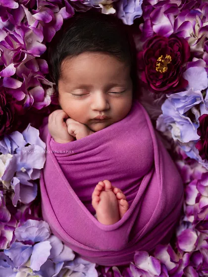 For families who love a touch of color, I adore creating vibrant, artistic setups like this. Nestled in a bed of soft purple petals, this little one looks like a precious flower bud. It shows how we can play with color while keeping the focus on your baby's peaceful sleep.
