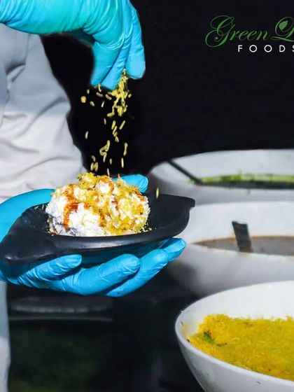 A chef carefully sprinkles sev over a plate of dahi puri. This attention to detail in the final garnish is part of my commitment to delivering a perfect chaat experience every time.
