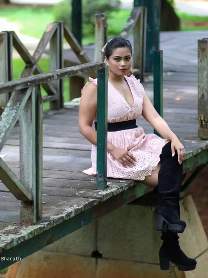A seated portrait on a wooden bridge, showing the contrast between the modern outfit and the rustic setting.