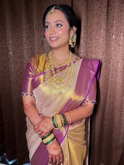 A full view of Archana's look, with the gold jewels and rich saree taking center stage, supported by flawless makeup.