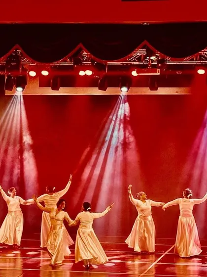 Another angle of the Indian Fusion piece, showing the dancers moving in unison under the warm red and white spotlights.