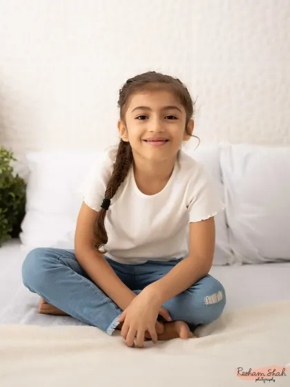 A simple, beautiful portrait on a clean, white bed setup. Her natural smile is all that's needed to make this photo shine.