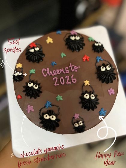 A fun cake inspired by the soot sprites from Studio Ghibli films. This chocolate ganache cake is decorated with piped sprites and colorful stars for a "Cheers to 2026" celebration.