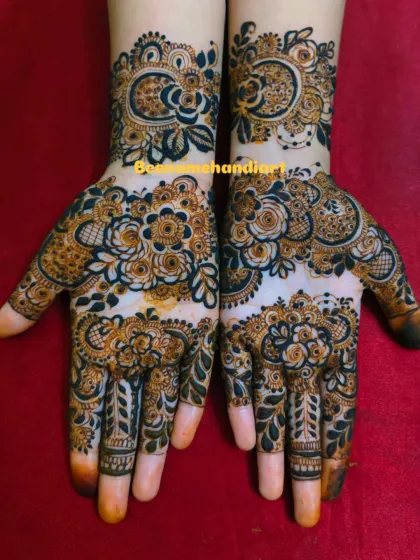 A pair of hands with heavy Arabic floral mehandi. This design covers the hands completely with bold, beautiful flowers.
