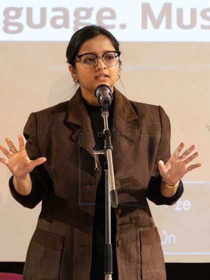 A poet using expressive hand gestures during her performance at the 'Verse & Voice' showcase. We teach artists how to use their whole body to tell a story.