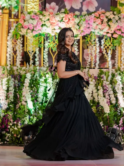 A classic black gown paired with elegant, side-swept curls. This timeless hairstyle is perfect for a sophisticated reception look.