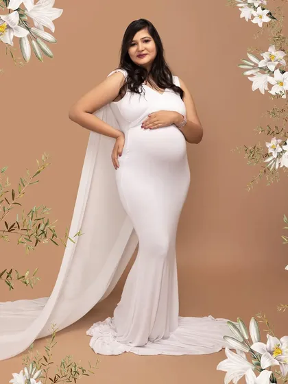The definition of elegance. This mother-to-be is wearing a beautiful white cape gown from my studio collection, creating a classic and graceful silhouette against a simple backdrop.