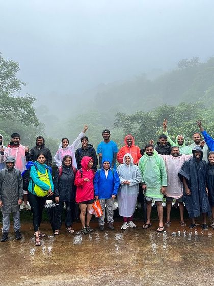 The group poses on a bridge in the pouring rain, fully equipped with raincoats and ready for more adventure.