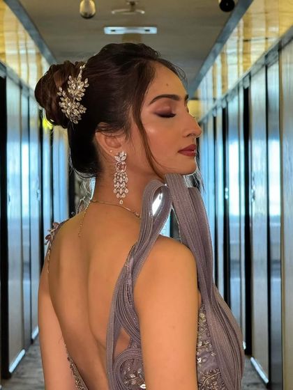 From the side, you can see the beautiful silhouette of the high bun and the intricate detail of the crystal hairpiece. This is a perfect look for a reception or cocktail gown.