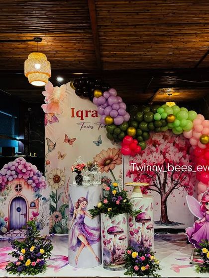 A beautiful, wide shot of the fairy garden theme we created in a restaurant. The decor elements, like the fairy house and colorful balloon arch, completely transform the space.