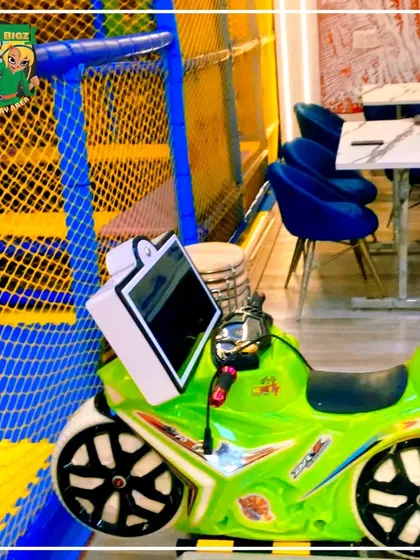 A close-up of one of our motorcycle kiddie rides, complete with a video screen for an interactive experience, positioned right next to the soft play area.