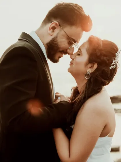 A beautiful, sun-flared close-up of a couple, capturing the warmth and intimacy of their connection. The golden light adds a dreamy, romantic quality to the portrait.