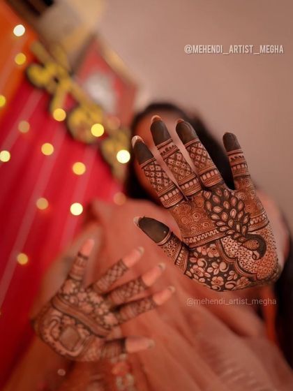 An artistic shot focusing on the peacock mehendi on one hand, with the other hand blurred, creating a sense of depth and highlighting the details.