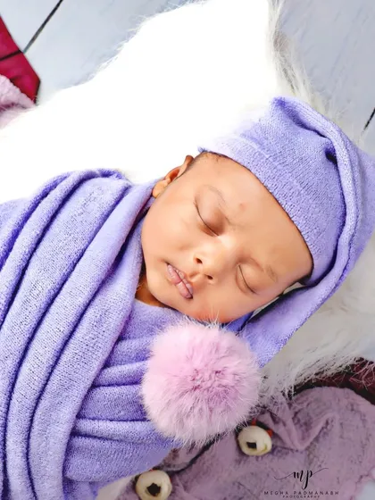 A close-up on the baby's face and the adorable pom-pom detail on his hat.