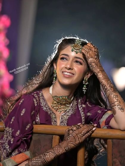 A beautiful bride resting her head on her hands, showing off her intricate mehandi.