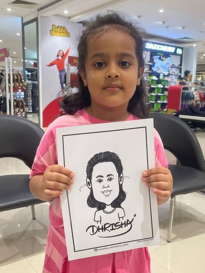 A little girl proudly holding up her caricature at a mall event. We love drawing for children and capturing their unique personalities.