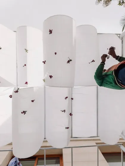 Another view of our team member stitching flowers onto the organic fabric canopies. This behind-the-scenes shot shows the dedication required to execute detailed, hand-crafted designs.